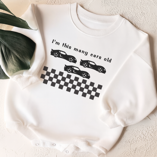 White sweatshirt with car-themed design on a light surface