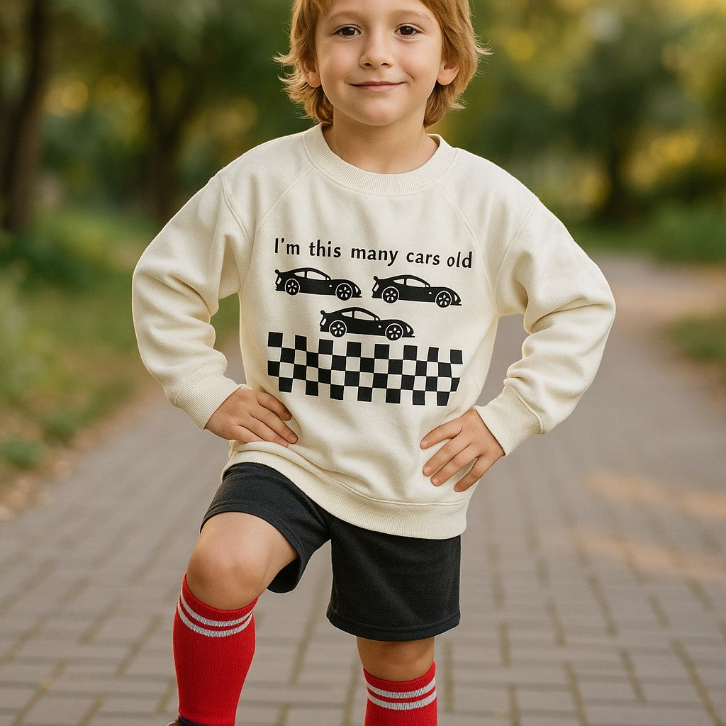 Child wearing a sweatshirt with car graphics and text outdoors