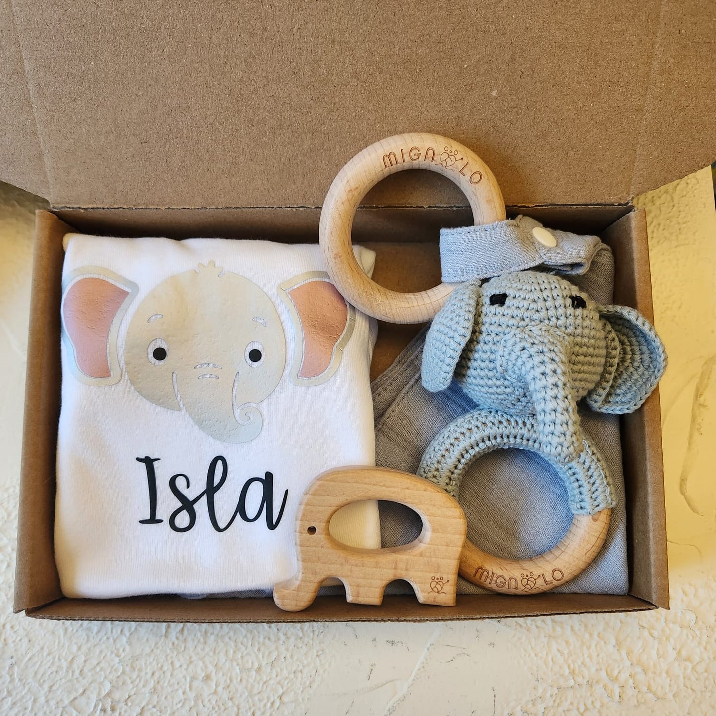 Baby gift set with elephant-themed t-shirt, teething rings, and toy in a box.