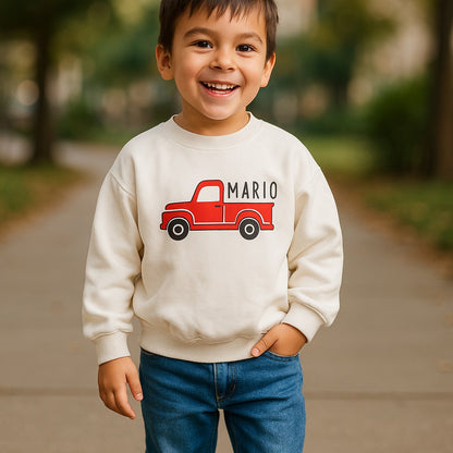 Child wearing a white sweatshirt with a red truck graphic and 'Mario' text, standing outdoors.
