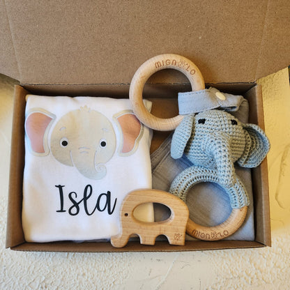 Baby gift set with elephant-themed t-shirt, teething rings, and toy in a box.